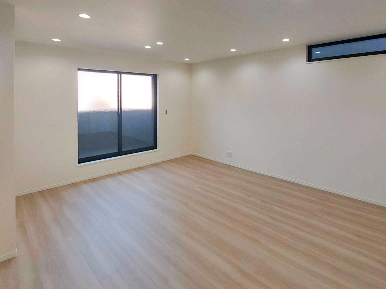 白色ダウンライトで均一に照らされた室内空間。明るさはあるが陰影が少なく、ホテルライクな雰囲気が出にくい照明状態の例