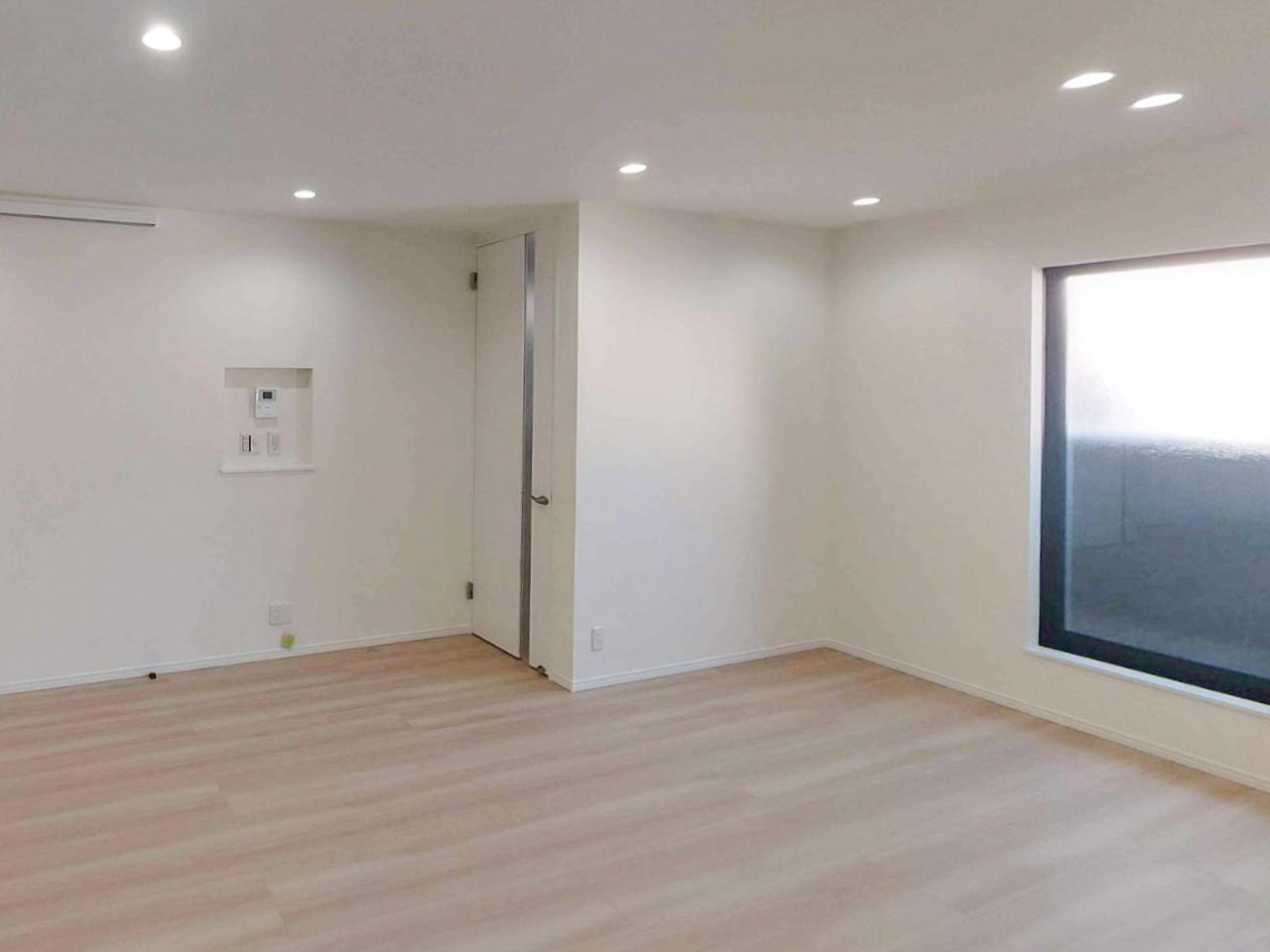 白色ダウンライトで均一に照らされた室内空間。明るさはあるが陰影が少なく、ホテルライクな雰囲気が出にくい照明状態の例